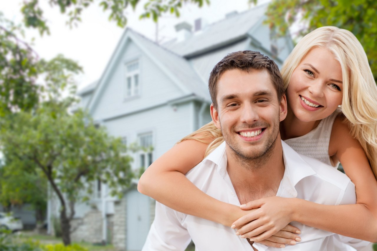 smiling couple hugging over house background
